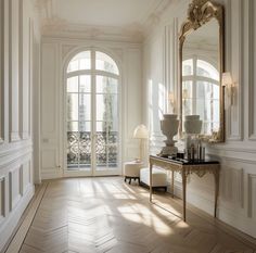 an elegant room with white walls and wood flooring, large arched windows, two lamps on either side of the door