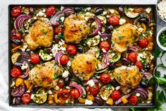 chicken and vegetables on a baking sheet with parsley, tomatoes, onions, olives, red onion, and feta cheese