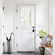 a white front door with an umbrella and flower pot on the bench next to it