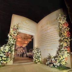 an open book with flowers on the front and side, in front of a building at night