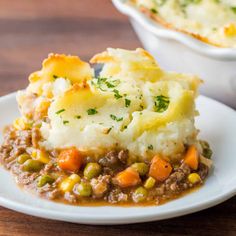 a white plate topped with mashed potatoes and peas next to a casserole dish