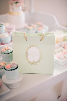 a table topped with cupcakes and cakes next to a bag filled with frosting