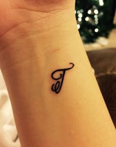 a small wrist tattoo with the letter f on it