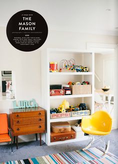 a yellow chair sitting in front of a white book shelf filled with books and toys