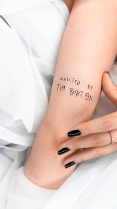 a woman laying on top of a bed with her arm tattooed