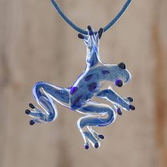 A spry blue glass frog with black accents handblown with a pipette and with torch worked details hangs from a blue waxed cotton cord in this pendant necklace. Handcrafted by Costa Rican artisan Guisselle Mora the frog has tiny air bubbles captured in the glass characteristic of handblown glass. A sliding knot in the cord allows the necklace length to easily be adjusted.