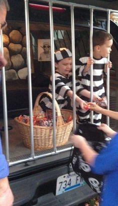 two boys in jail cell with their hands on the back of a car and one boy is holding a bag