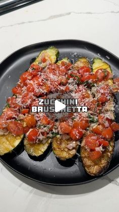 a black plate topped with zucchini boats covered in tomatoes and sauce on top of a white table