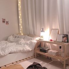 an unmade bed with white sheets and lights