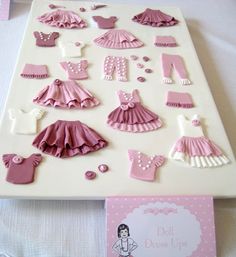 there is a cake that has pink and white decorations on it, including dresses and shoes