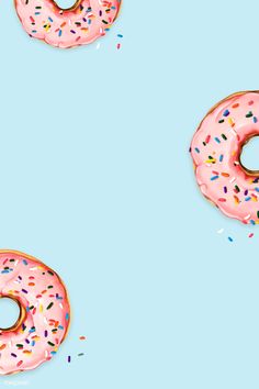 two donuts with pink frosting and sprinkles on a blue background