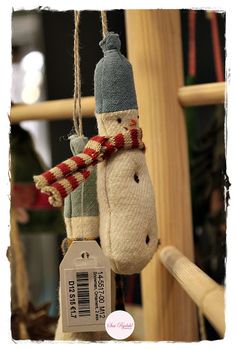 a snowman ornament hanging from a wooden pole with a tag attached to it