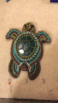 a beaded turtle brooch sitting on top of a table