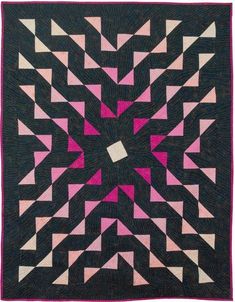 a black and pink quilt with an intricate design on the center, surrounded by smaller triangles