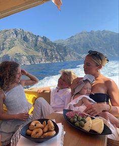 three people sitting at a table with plates of food in front of them on a boat