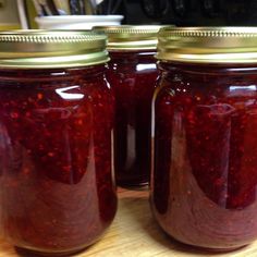 three jars filled with red liquid sitting on top of a wooden table