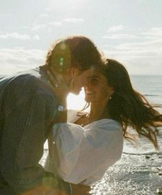 a man and woman kissing on the beach