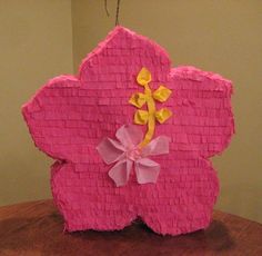 a pink flower made out of paper sitting on top of a wooden table next to a wall