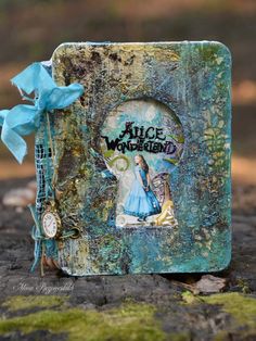 an altered book with a blue bow on it's cover and the words alice wonderland written