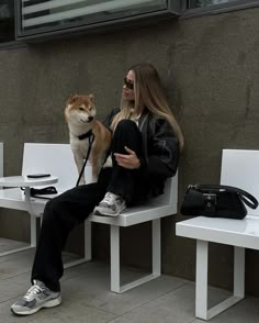 a woman sitting on a bench next to a dog