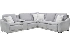 a grey sectional couch with pillows on it's back and arms, facing the camera