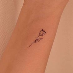 a single flower tattoo on the wrist is shown in black ink and has a thin line drawing