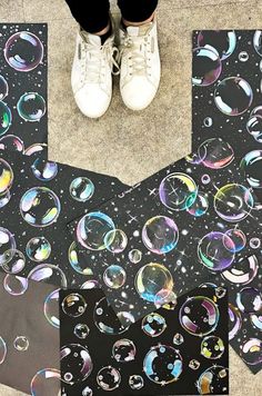 a pair of white shoes standing on top of a black floor covered in soap bubbles