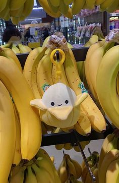 bunches of bananas hanging from hooks in a grocery store with a smiley face on them