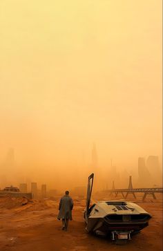 a man is walking towards a boat in the middle of an empty desert with buildings in the background