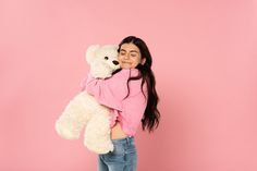 a girl in pink shirt holding a white teddy bear