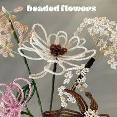 there are some flowers made out of beaded wire and beads on the stems with words above them