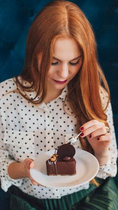 a woman holding a plate with a piece of chocolate cake on it