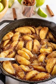 a skillet filled with apples and cinnamon on top of a white table next to an apple