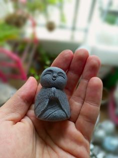 a hand holding a small gray figurine in it's palm