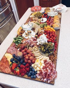 a large platter of meats, cheeses and fruit on a kitchen counter