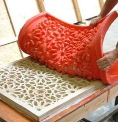 a man is working on a red vase