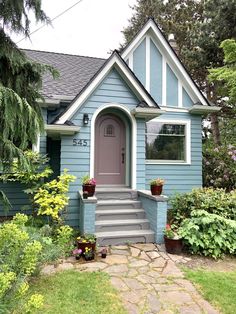 a blue house with flowers in the front yard and steps leading up to the door