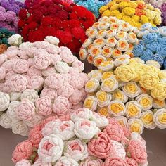 many crocheted flowers are arranged on the floor in rows, all different colors