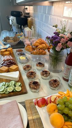 an assortment of food is displayed on a kitchen counter with flowers in a vase and other foodstuffs