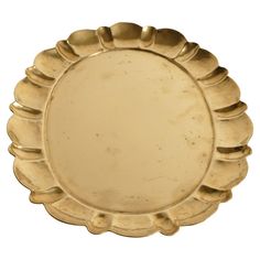 an antique gold plate with scalloped edges on a white background for use as a serving platter