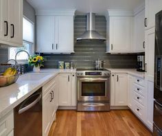 a kitchen with white cabinets, stainless steel appliances and wood floors is pictured in this image