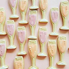 decorated cookies in the shape of champagne glasses on a pink background with white dots and polka dots