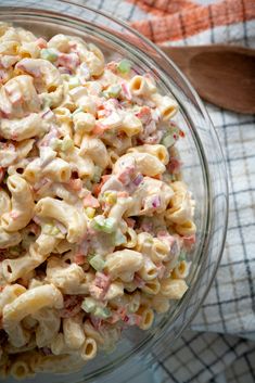 a glass bowl filled with macaroni salad on top of a checkered cloth