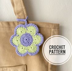 a crochet flower is hanging on the side of a bag