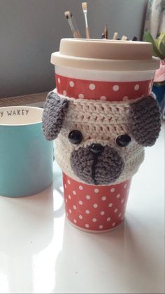 a coffee cup with a crocheted dog on it