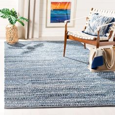 a living room with a blue rug and wooden chair in it, next to a potted plant