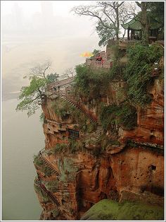 a cliff with stairs leading to the top and trees growing out of it's sides