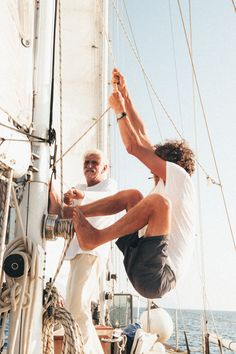 two men on a sailboat doing tricks in the air