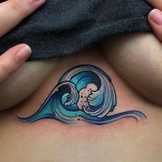 a woman's stomach with a tattoo on the side of her body and an ocean wave coming out of it