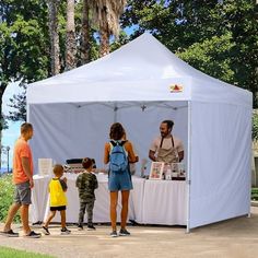 a group of people standing in front of a white tent